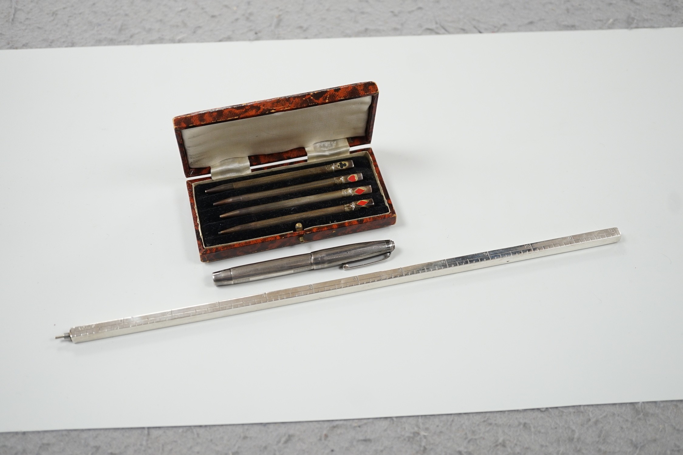 An engine-turned silver fountain pen, a cased set of four silver Bridge pencils and a silver combination pencil/rule